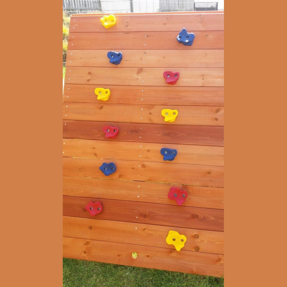 Wooden climbing wall with colorful rock holds on a grassy background