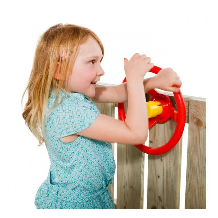 Child playing with a red playground steering wheel on a wooden fence