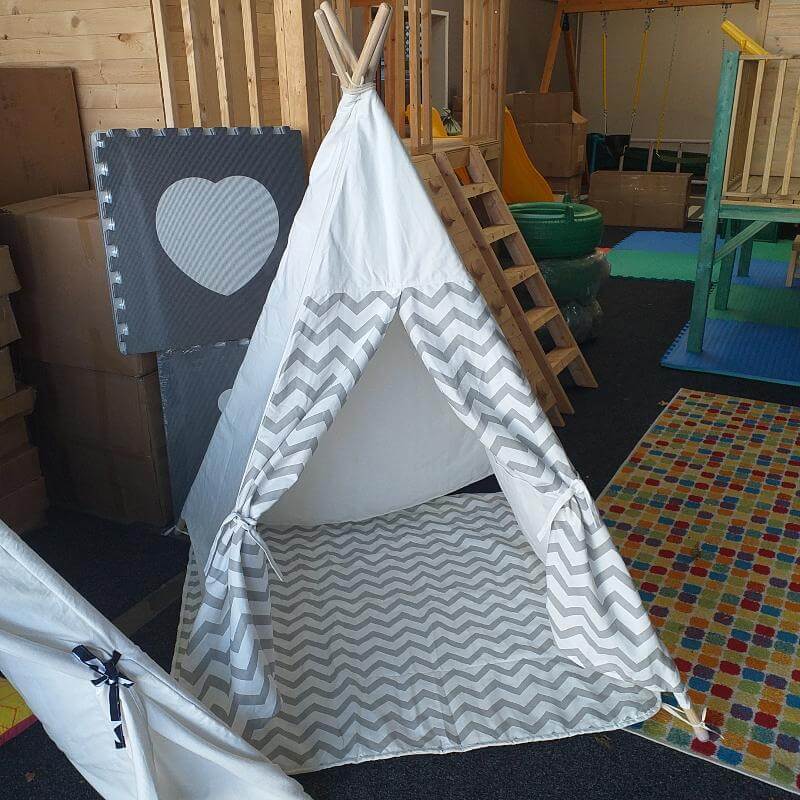 Children's play area with a white teepee tent featuring gray zigzag patterns.