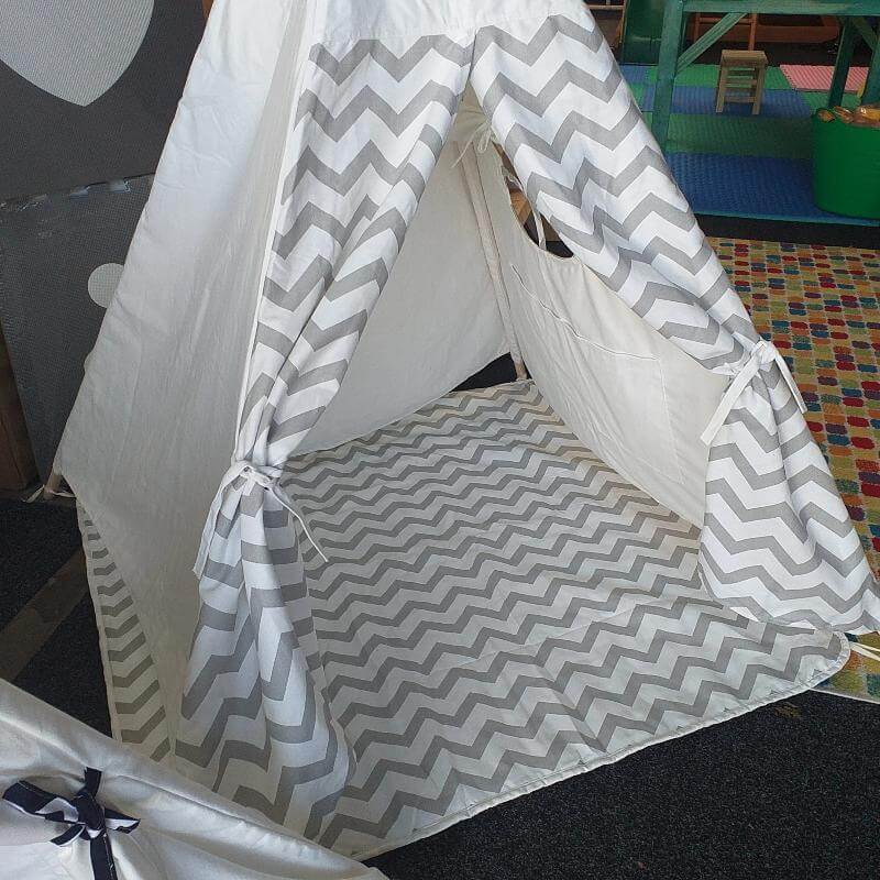 Children's play tent with gray and white chevron pattern on a colorful floor.