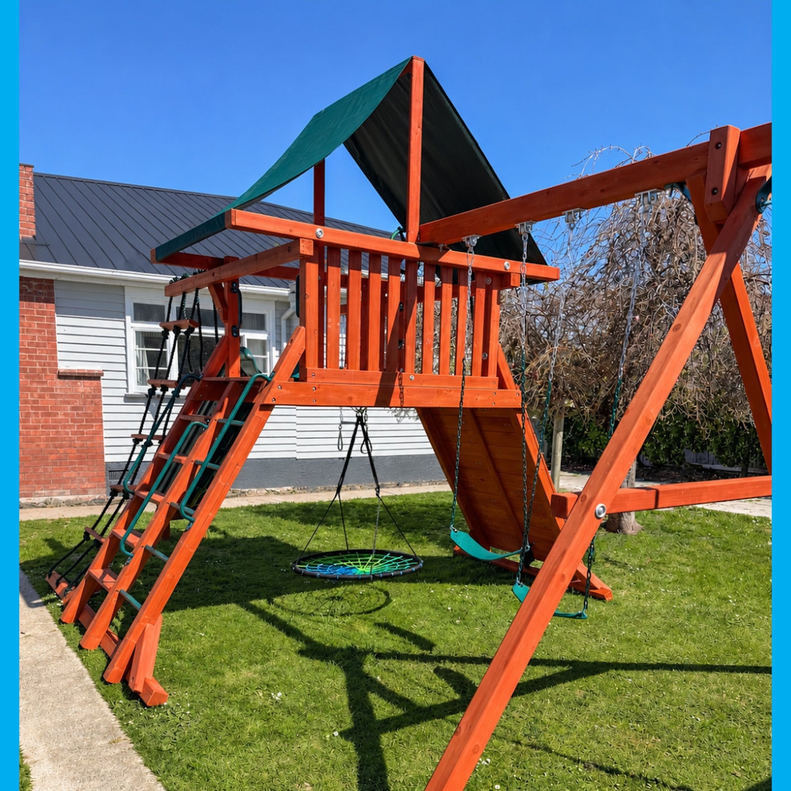 wooden cedar playground in NZ backyard with nest swing, belt swings, slide and climbing rope and walls