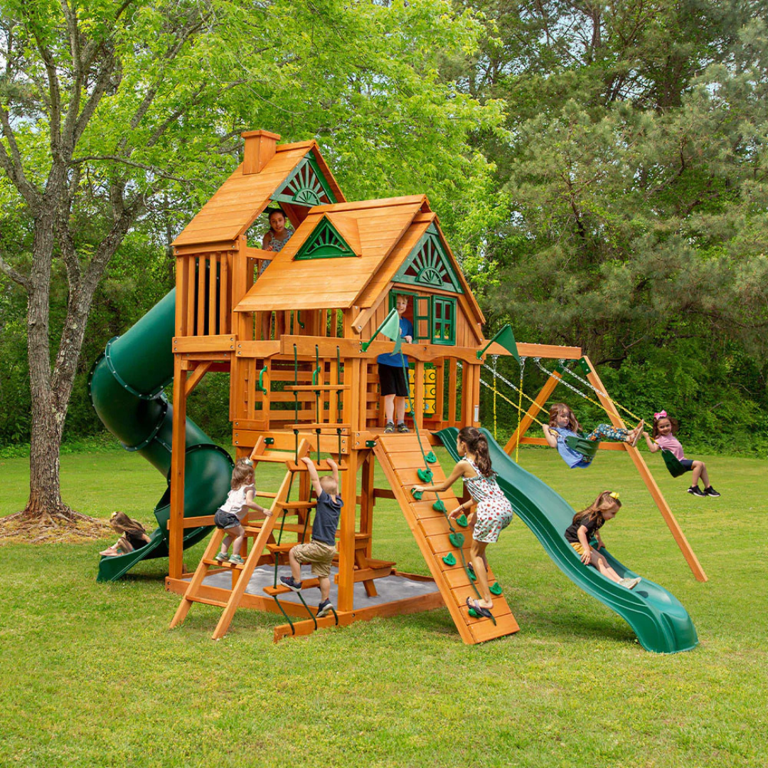 Kids playing on an outdoor wooden playground with green tube and wave  slides
