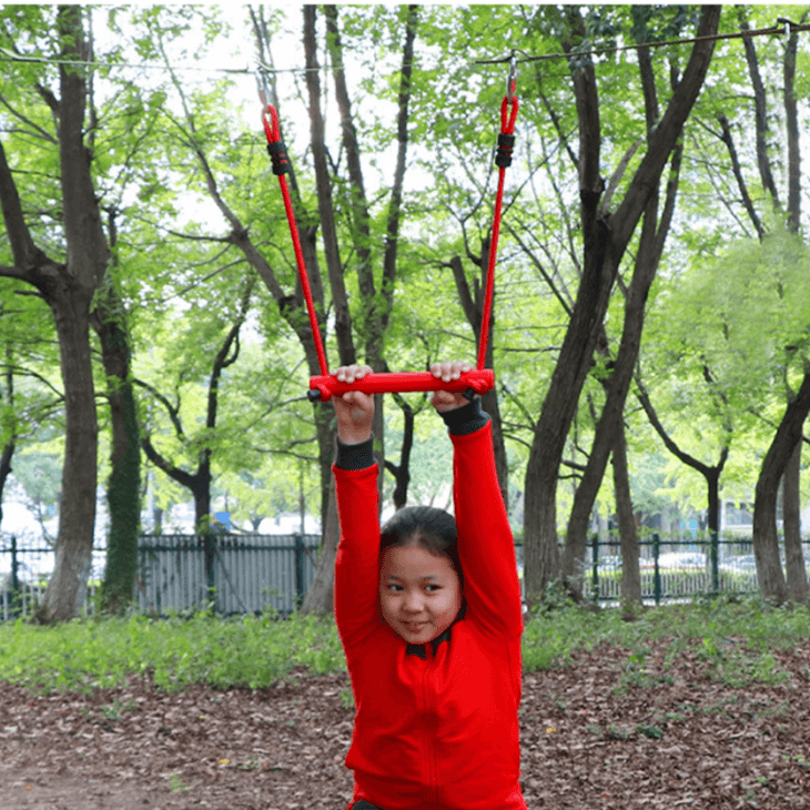 girl on a red trapeze swing in a red ninja outfit playing in a backyard