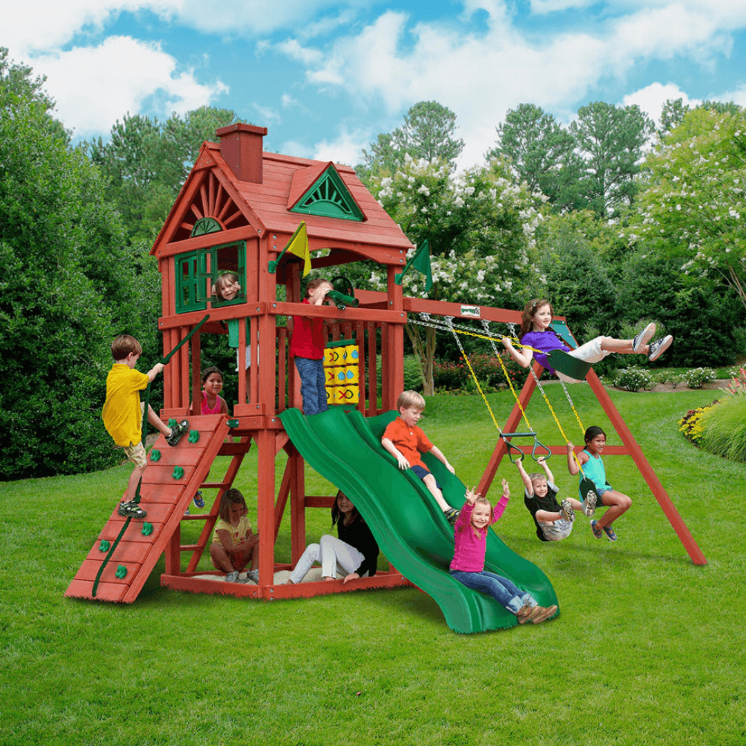Children playing on a red playset with green slide and swings in nz backyard