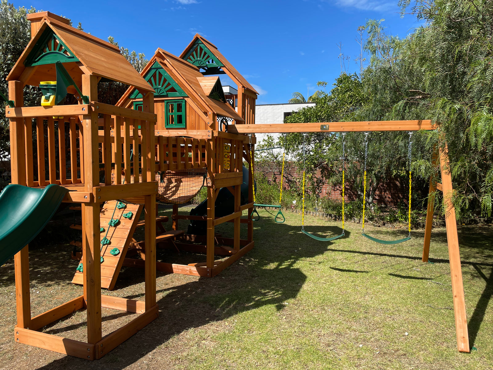 Wooden outdoor playground kit-set with slides and swings in a kiwi backyard