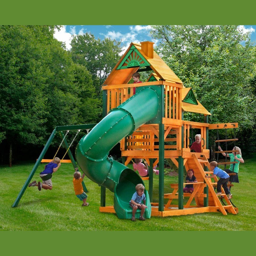 Children playing on a wooden playground set with green slide and swings in nz backyard