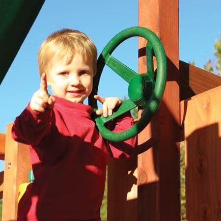Child playing on a playground structure with a green steering wheel
