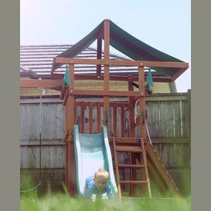 Child playing on a wooden playground set with a swing and slide in a nz backyard.