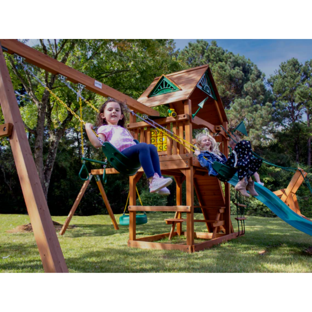 Children playing on a wooden swing set with a slide in a backyard setting.
