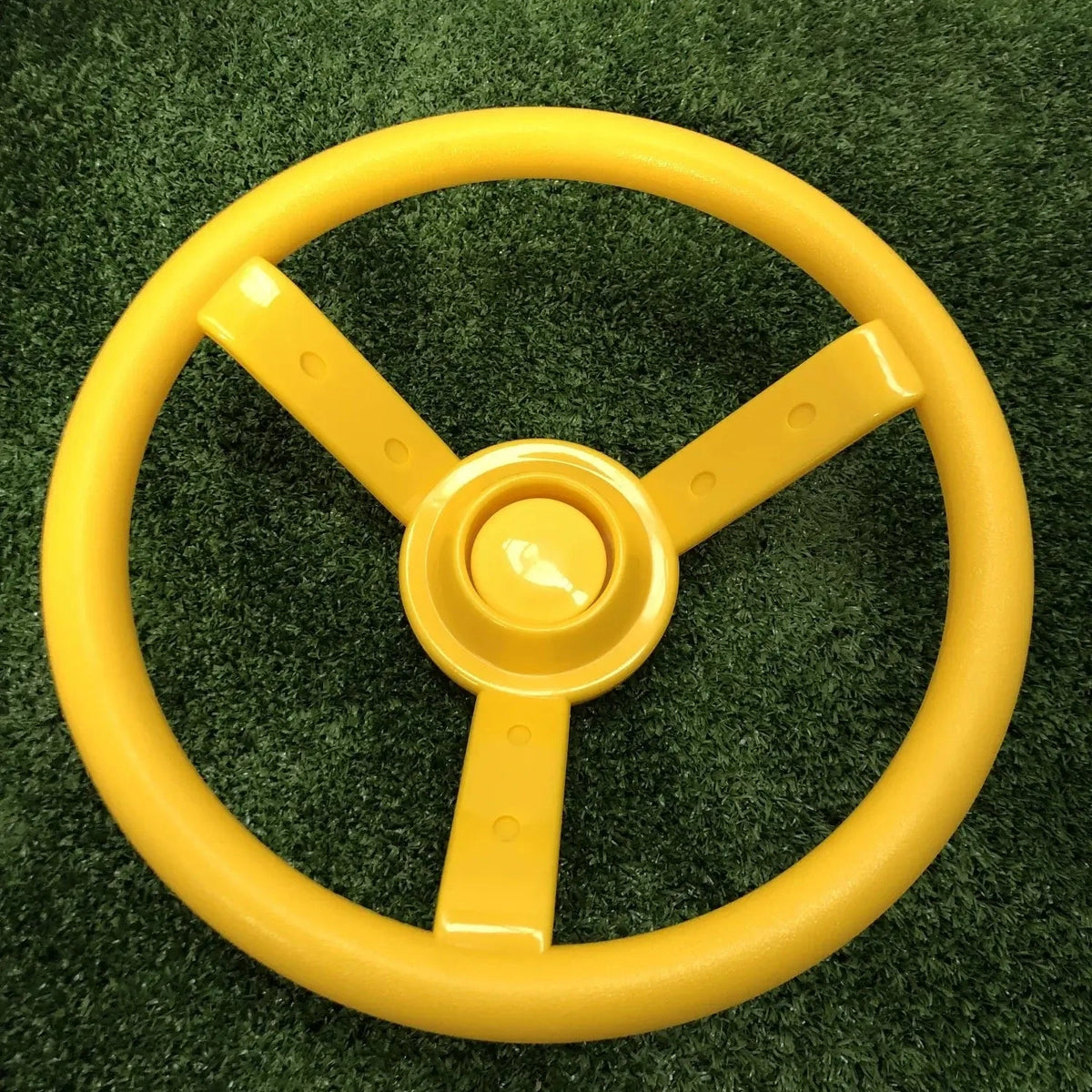 Yellow steering wheel for playground on a green grass background