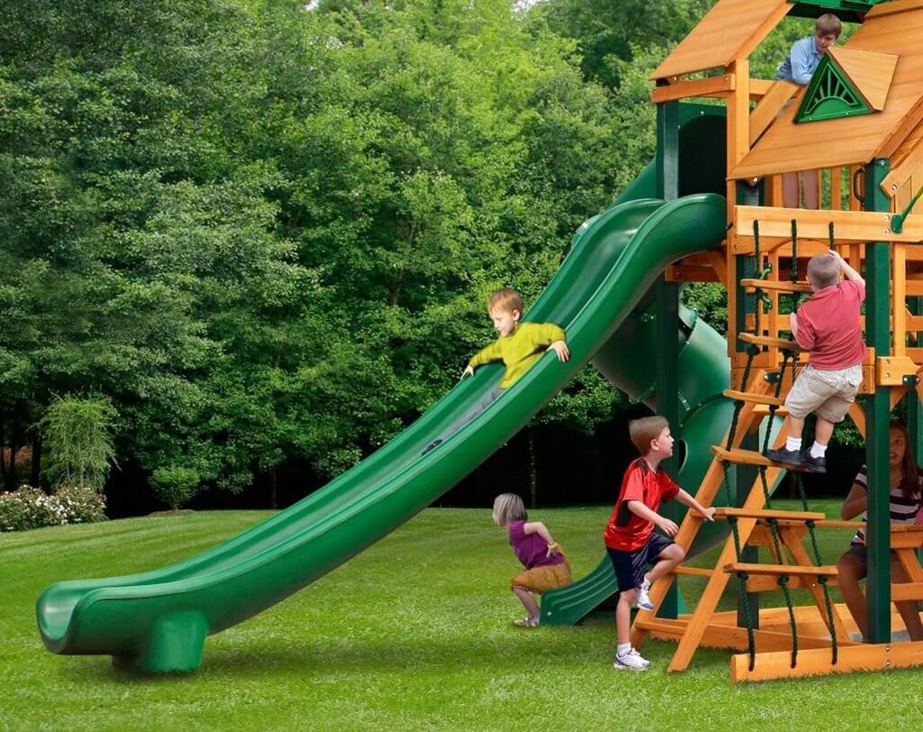 Children on playground and sliding down green slide