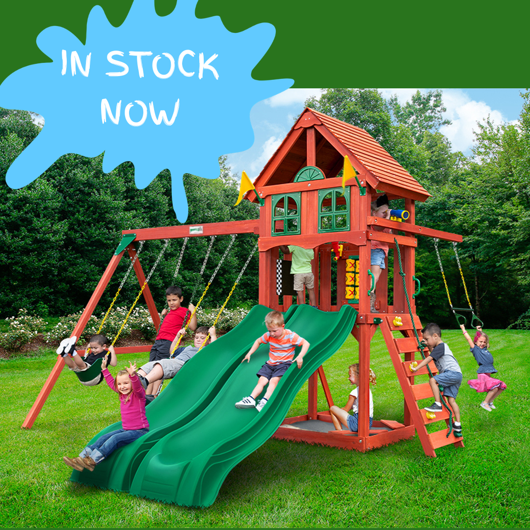 Children playing on a wooden swing set with green slide in a nz backyard